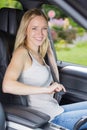 Beautiful young happy woman fastens seat belt in car