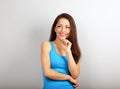 Beautiful young happy woman with finger under the face thinking and looking up in casual blue shirt and long hair. Closeup Royalty Free Stock Photo