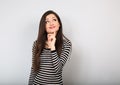 Beautiful young happy woman with finger under the face thinking and looking up in casual shirt and long hair. Closeup portrait Royalty Free Stock Photo