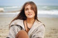 Beautiful young happy woman portrait against seascape, long hair fluttering in the wind, looking at camera, casual autumn fashion