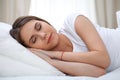 Beautiful young and happy woman sleeping while lying in bed comfortably and blissfully smiling