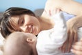 Beautiful young happy woman with her newborn baby lies on the couch, family love and care concept Royalty Free Stock Photo