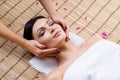 Beautiful, young and healthy woman on bamboo mat in spa salon having face massage. Royalty Free Stock Photo