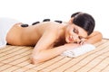 Beautiful, young and healthy woman on bamboo mat in spa salon is having hot stone massage. Royalty Free Stock Photo