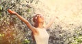 Beautiful young hippie woman raising her hands up wearing floral headband, sunglasses in spring blooming garden on white flowers Royalty Free Stock Photo