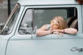 A beautiful young hippie woman in yellow sunglasses looks out the window of a blue vintage minivan. Make love, not war Royalty Free Stock Photo