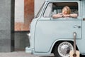 A beautiful young hippie woman in yellow sunglasses looks out the window of a blue vintage minivan. Make love, not war Royalty Free Stock Photo