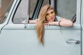 A beautiful young hippie woman in yellow sunglasses looks out the window of a blue vintage minivan. Make love, not war Royalty Free Stock Photo
