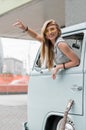 A beautiful young hippie woman in yellow sunglasses looks out the window of a blue vintage minivan. Make love, not war Royalty Free Stock Photo