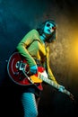 Beautiful young hipster woman with curly hair with red guitar in neon lights. Rock musician is playing electrical guitar Royalty Free Stock Photo