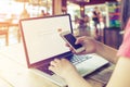 beautiful young hipster woman`s hands busy working on her laptop, female using cell telephone sitting at wooden table Royalty Free Stock Photo