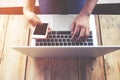 Beautiful young hipster woman`s hands busy working on her laptop, female using cell telephone sitting at wooden table Royalty Free Stock Photo