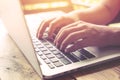 beautiful young hipster woman`s hands busy working on her laptop sitting at wooden table in a coffee shop