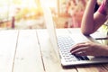 beautiful young hipster woman`s hands busy working on her laptop sitting at wooden table in a coffee shop Royalty Free Stock Photo