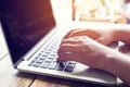 beautiful young hipster woman`s hands busy working on her laptop sitting at wooden table in a coffee shop Royalty Free Stock Photo