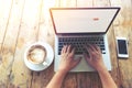 Beautiful young hipster woman`s hands busy working on her laptop sitting at wooden table in a coffee shop Royalty Free Stock Photo