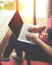 Beautiful young hipster woman`s hands busy working on her laptop sitting at wooden table in a coffee shop Royalty Free Stock Photo