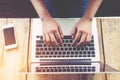 Beautiful young hipster woman`s hands busy working on her laptop sitting at wooden table in a coffee shop Royalty Free Stock Photo