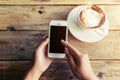 Beautiful young hipster woman`s hands holding mobile smart phone with hot coffee cup at cafe shop, Royalty Free Stock Photo