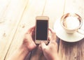 beautiful young hipster woman`s hands holding mobile smart phone with hot coffee cup at cafe shop Royalty Free Stock Photo