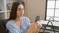 Beautiful young hispanic woman boss, working proficiently on her smartphone in office, texting messages, embodying professional Royalty Free Stock Photo