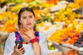 Beautiful young hispanic woman wearing andean traditional blouse using mobile phone inside fruit market, thoughtful Royalty Free Stock Photo