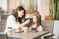 Mother feeding her daughter with cake at the cafe Royalty Free Stock Photo