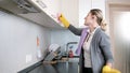 Beautiful young housewife listening music with earphones while doing housework Royalty Free Stock Photo