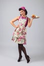 Beautiful young housewife in purple dress and apron with dessert