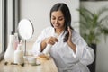Beautiful young indian woman applying serum on her hair Royalty Free Stock Photo
