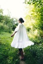 Beautiful young Indian woman smelling flower in the park, wearing white dress Royalty Free Stock Photo
