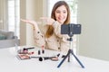 Beautiful young influencer woman recording make up video tutorial amazed and smiling to the camera while presenting with hand and Royalty Free Stock Photo