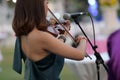 A beautiful young international musician playing the violin in an outdoor lawn