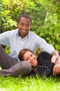 Beautiful young interracial couple in sitting garden environment, embracing and smiling happily to camera Royalty Free Stock Photo