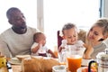 Young interracial family with little children having breakfast. Royalty Free Stock Photo