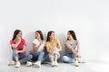 Beautiful young ladies in jeans and colorful t-shirts near white wall. Woman`s Day Royalty Free Stock Photo