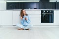 Beautiful young lady in casual clothes tasting delicious chocolate while sitting on the wooden floor in the domestic Royalty Free Stock Photo