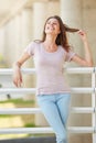 Beautiful young lady standing against railing outdoors and smiling Royalty Free Stock Photo