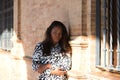 beautiful and young latin black woman is in the most important and biggest square of seville. She is leaning against the brick Royalty Free Stock Photo