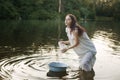 Young laundress in nightie washing clothes in the river