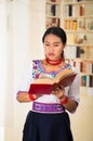 Beautiful young lawyer wearing black skirt, traditional andean blouse with necklace, standing posing for camera, holding Royalty Free Stock Photo