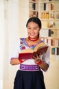 Beautiful young lawyer wearing black skirt, traditional andean blouse with necklace, standing posing for camera, holding Royalty Free Stock Photo