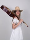 Beautiful young leggy blond Country girl in a litl white dress and cowboy hat with a guitar Royalty Free Stock Photo