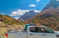 Beautiful young girl lies on the roof of a pickup truck on the background of the beautiful mountains of Tajikistan