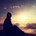 Beautiful young long hair girl tourist enjoy daybreak on the sharp corner of sandstone rock and watch over valley to Sun. Royalty Free Stock Photo