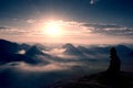 Beautiful young long hair girl tourist enjoy daybreak on the sharp corner of sandstone rock and watch over valley to Sun. Royalty Free Stock Photo