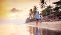 Beautiful young love happy couple walking arm in arm on the beach at sunset during the honeymoon vacation travel Royalty Free Stock Photo