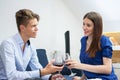 Beautiful young loving couple sitting close to each other and drinking red wine, Royalty Free Stock Photo