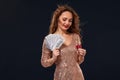 Image of lucky happy woman with brown long hair with fan of 100 dollar bills, lots of cash money, over black background Royalty Free Stock Photo