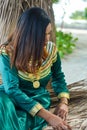 Beautiful maldivian woman in national dress making sheets for roof building